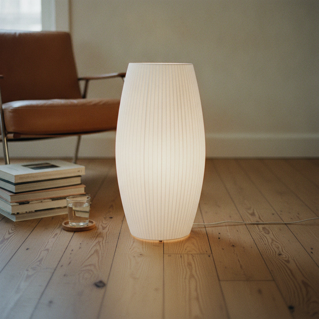 Glowing ribbed paper lamp on a wooden floor beside a caramel leather chair